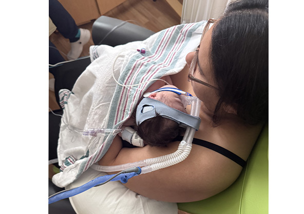 Ashley Yanes holds her newborn Vivian in the NICU while on breathing support