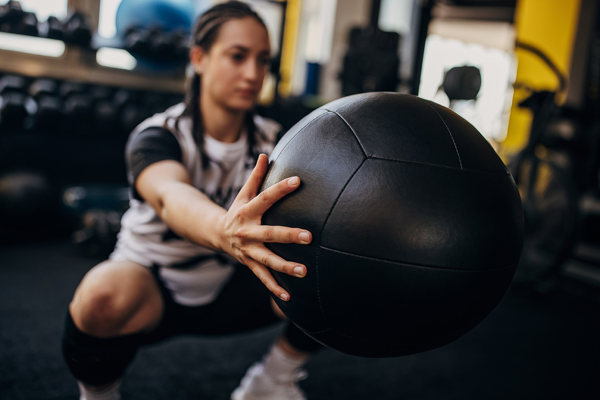 Young woman exercising medicine ball in gym alone